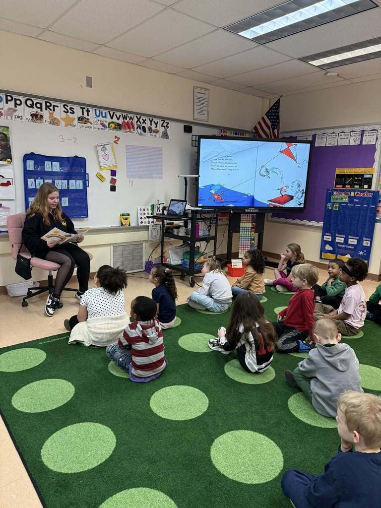 A women reading to students in a classroom. 