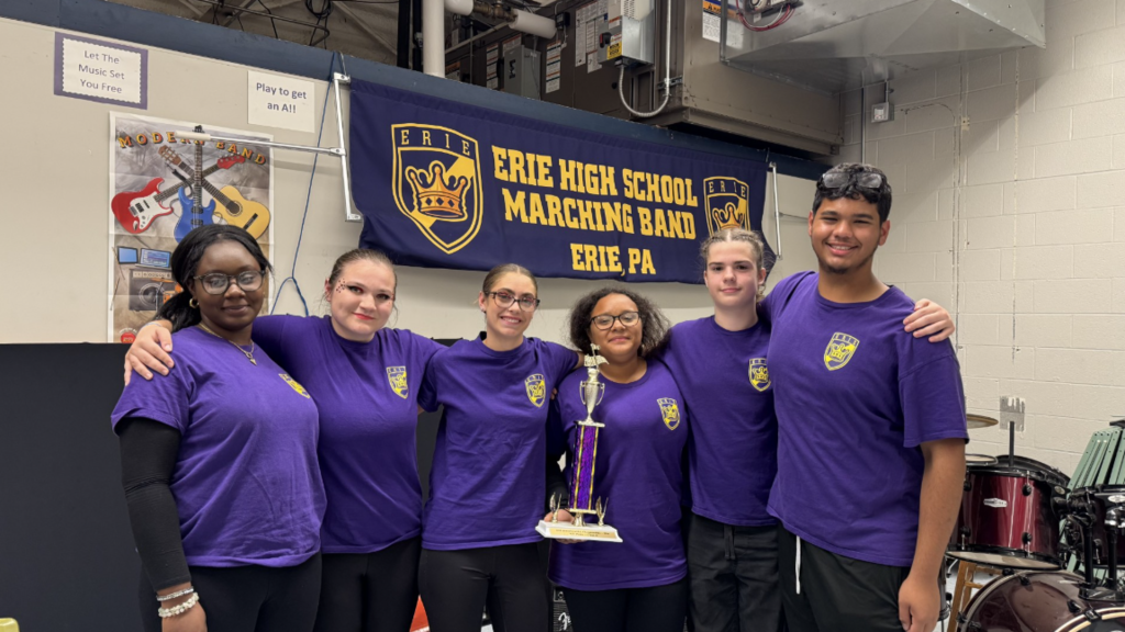 Erie High School Marching Band smiling and holding a trophy. 