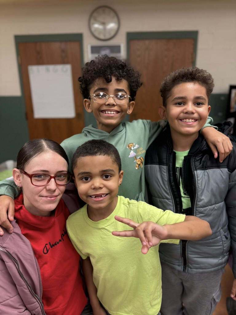 A women smiling and hugging three young boys. 