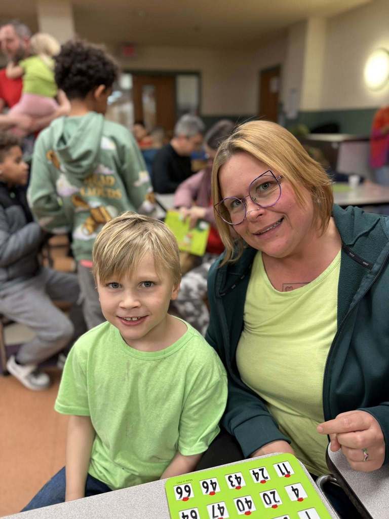 A women and young boy wearing green and smiling. 