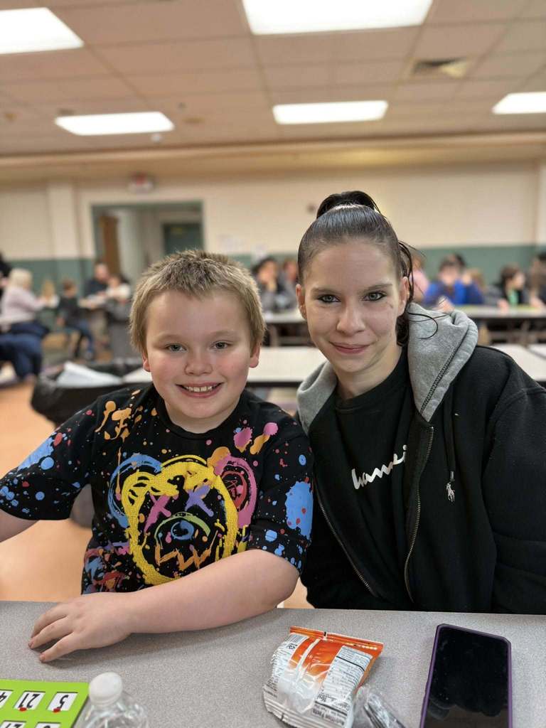 A women sitting next to a young boy and smiling. 