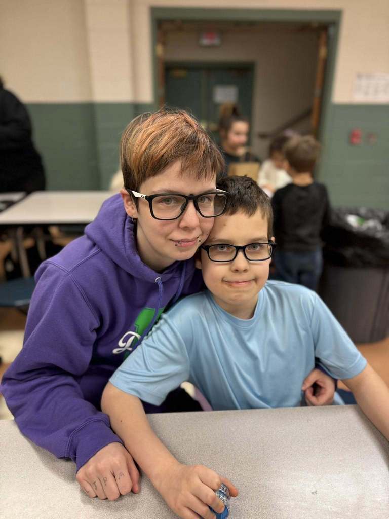 A women hugging a young boy and they both are smiling. 