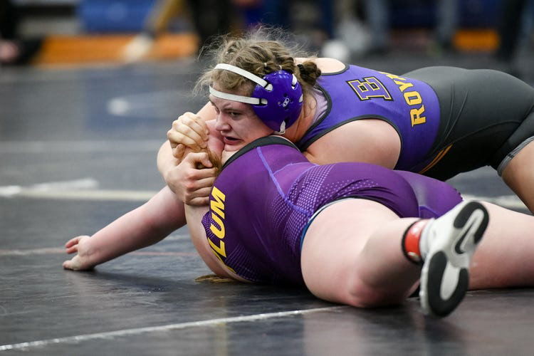 Two girls are wrestling at a match. 