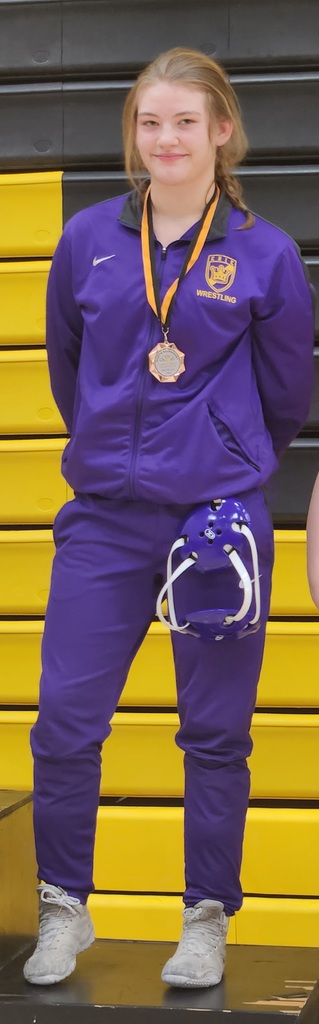A young girl is dressed in her Erie High School team uniform and is wearing a metal. 