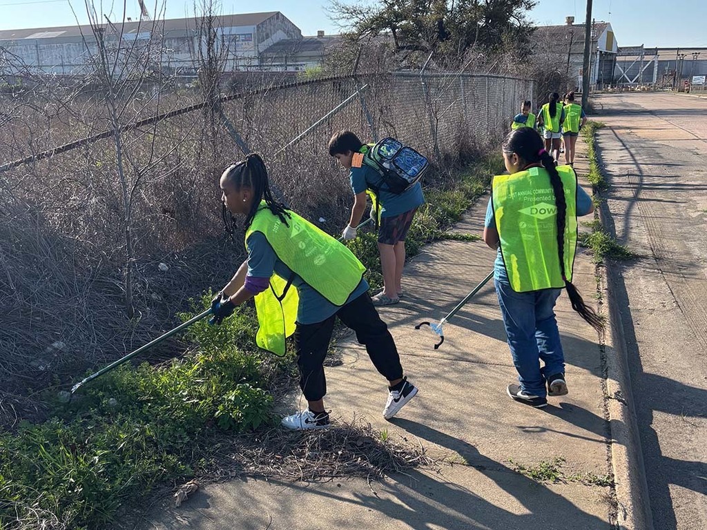 Elementary students picking up trash from the sidewalk