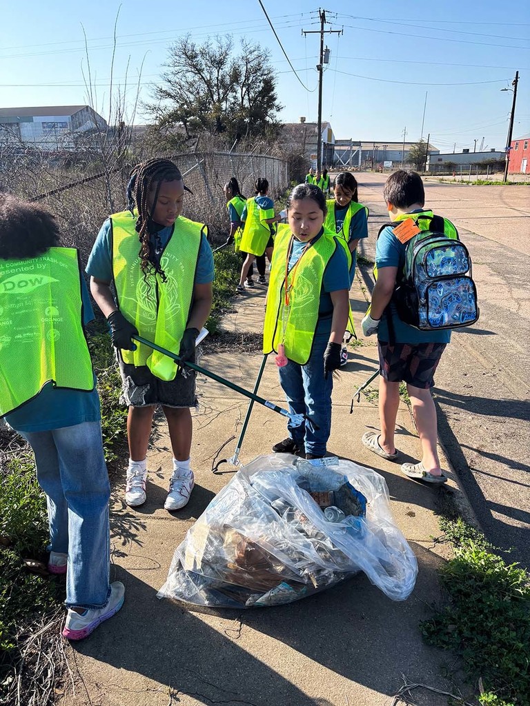 Elementary students picking up trash from the sidewalk