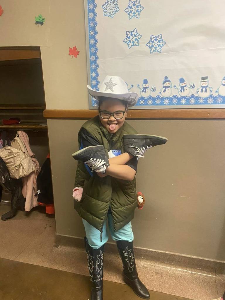 A student wearing shoes on his hands and a cowboy hat.