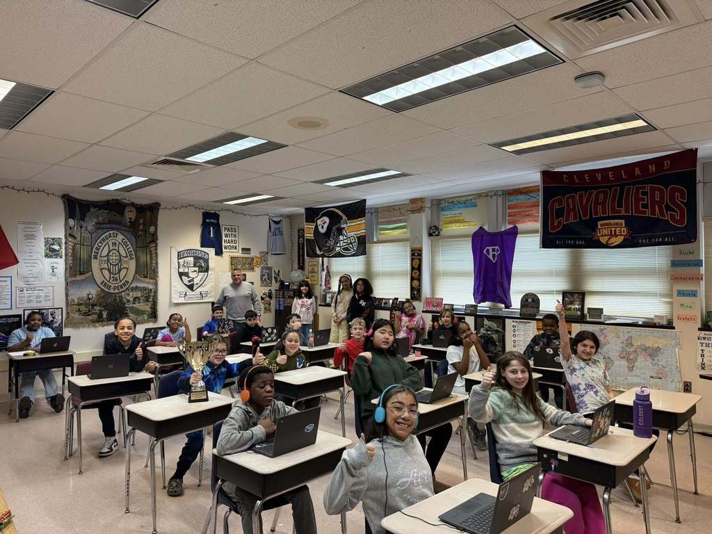 Students sitting in front of their computers and smiling in class.