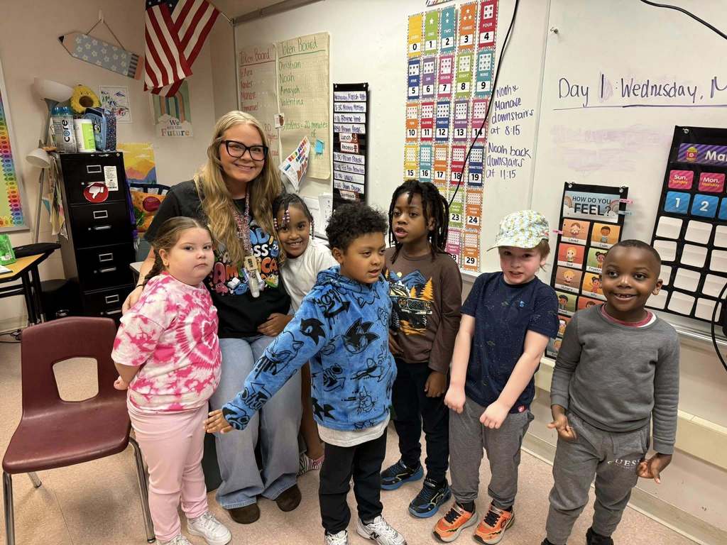 Students and teacher smiling in a classroom. 
