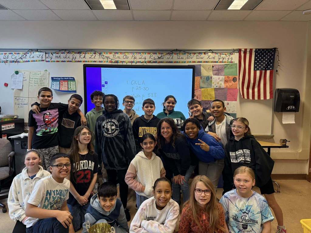 Students and teacher smiling in a classroom. 
