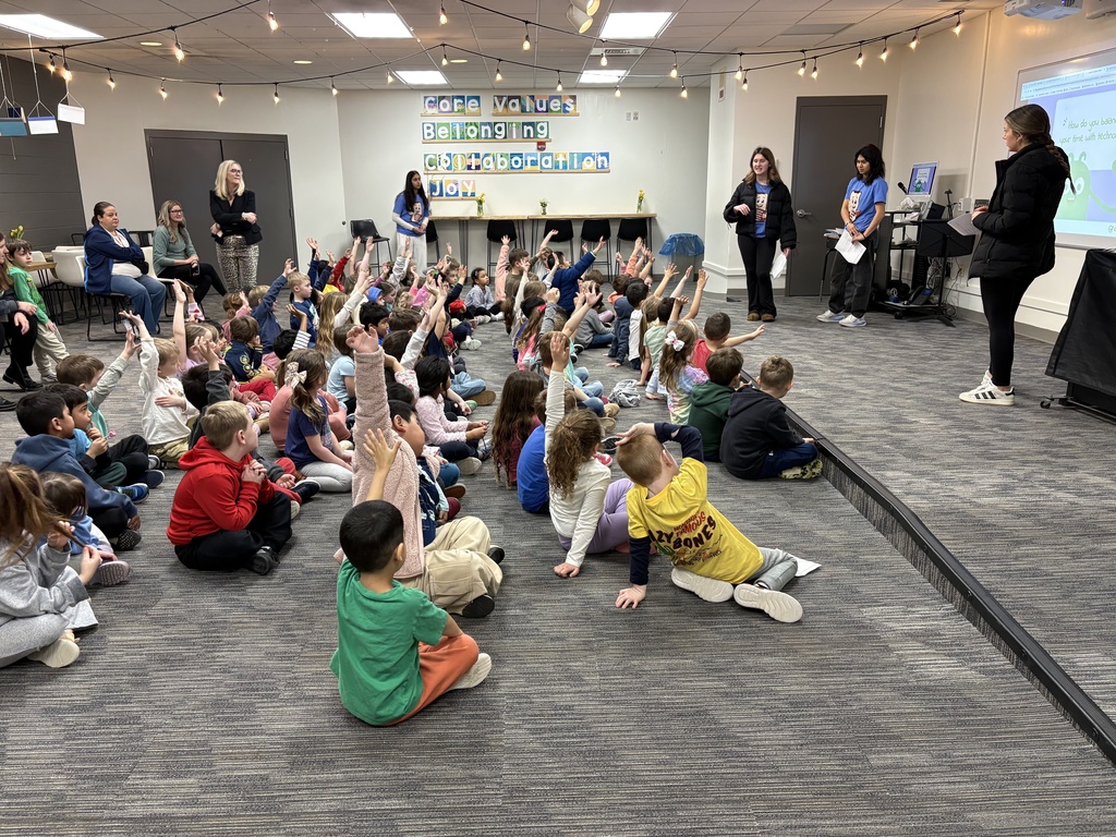 Kindergarten students raising their hands, wanting to participate in the question, "How do you balance your time with technology?"