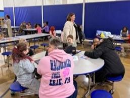Adults and students at a circular table in a cafeteria. 