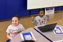 Two young girls working on a project and they are excited and smiling. 