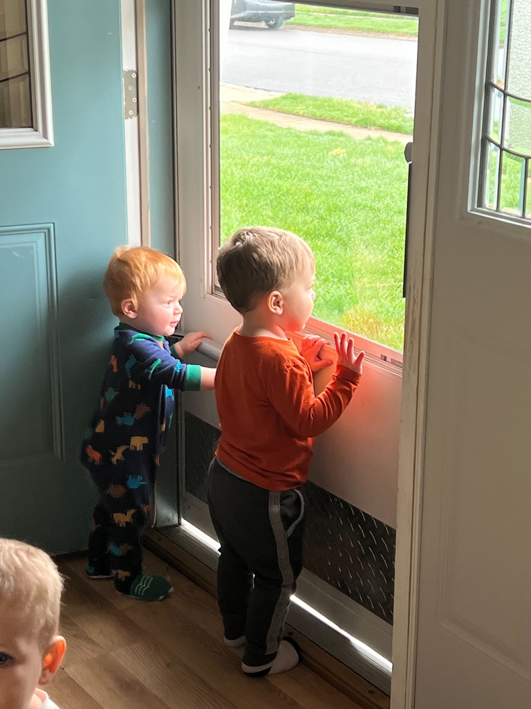 Two little boys looking out the door for the bus driver to come.
