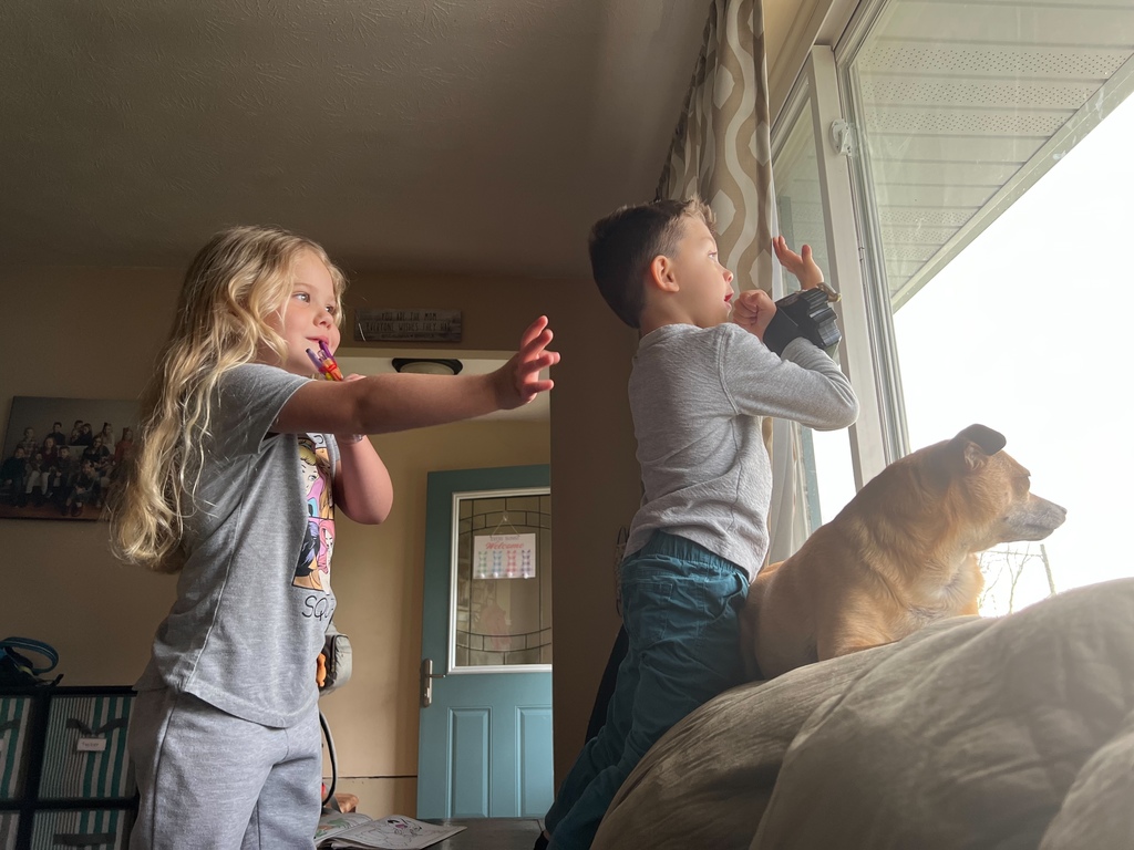 Two children waving to the Mr. Tom as he approaches the bus stop.