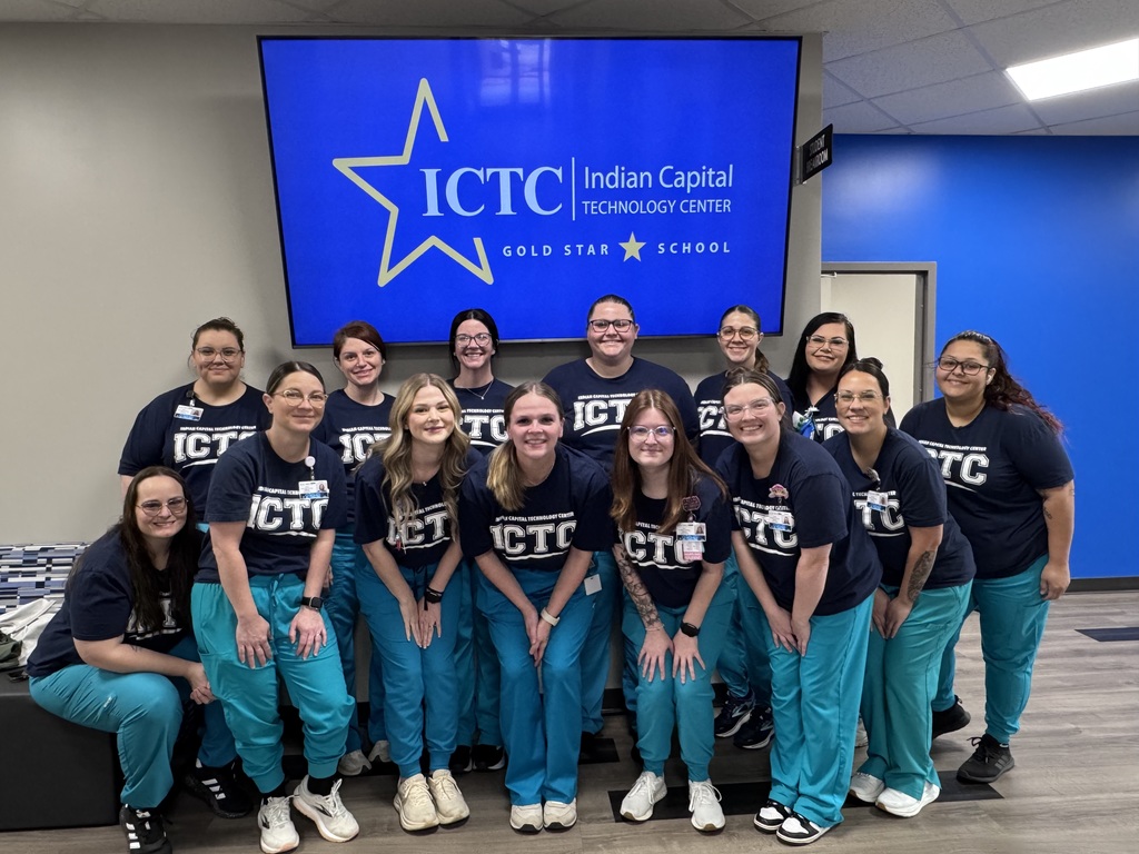 A group of people in matching blue shirts and green pants posing in front of a blue screen.
