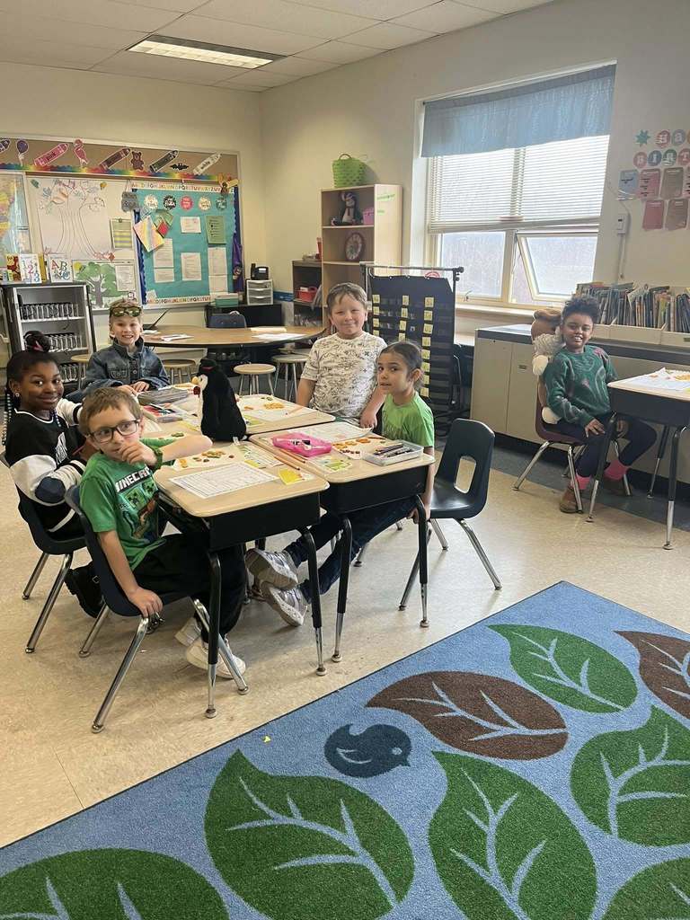 Students smiling while they do an activity at their desks in class. 