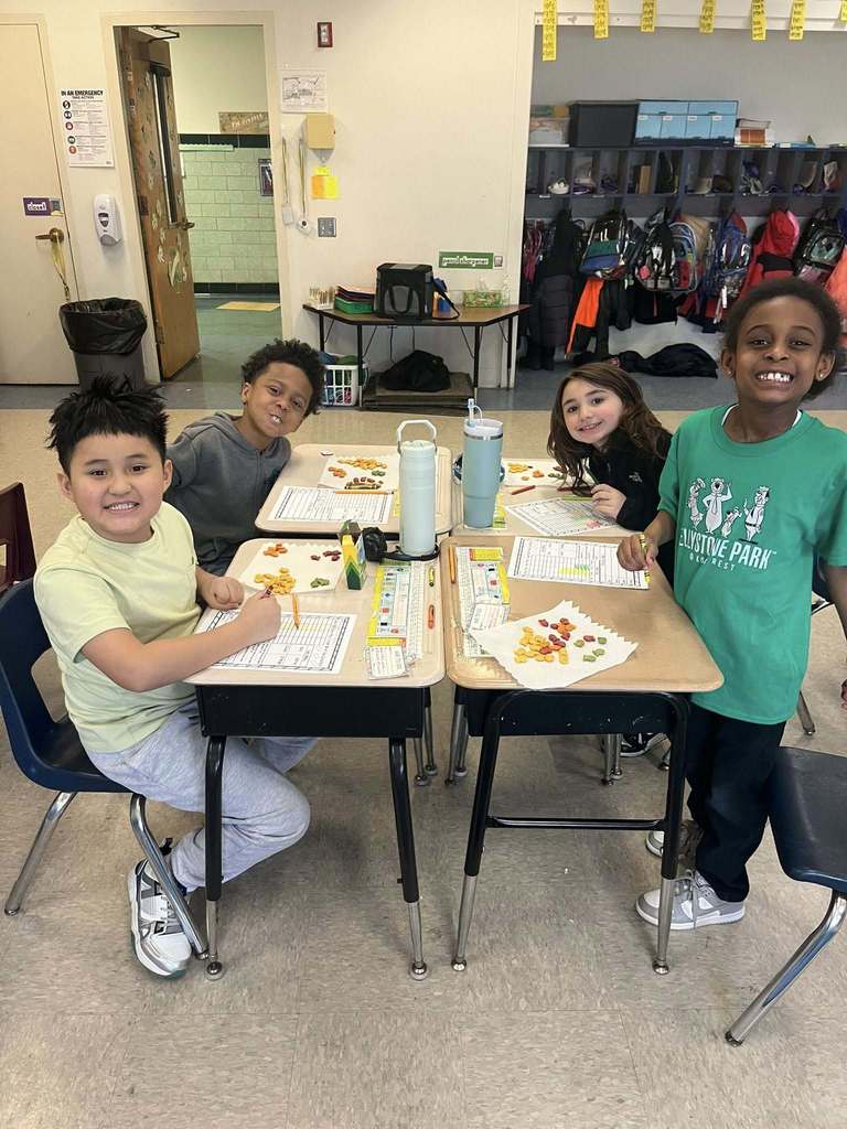 Students smiling while they do an activity at their desks in class. 