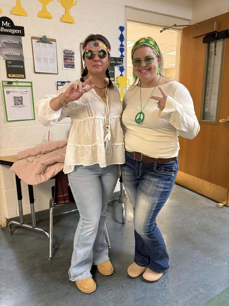 Two teachers wearing glasses, white shirts, and jeans to look like they are from the 70s.