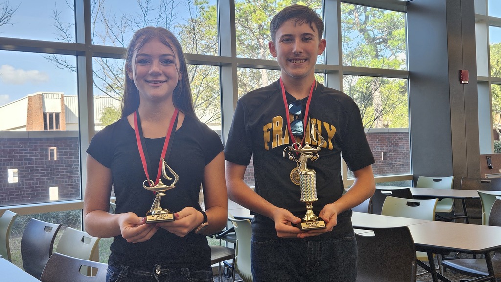 Two students hold their individual trophies.