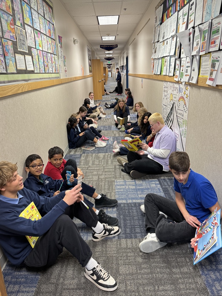 students paired up reading  in the hallway