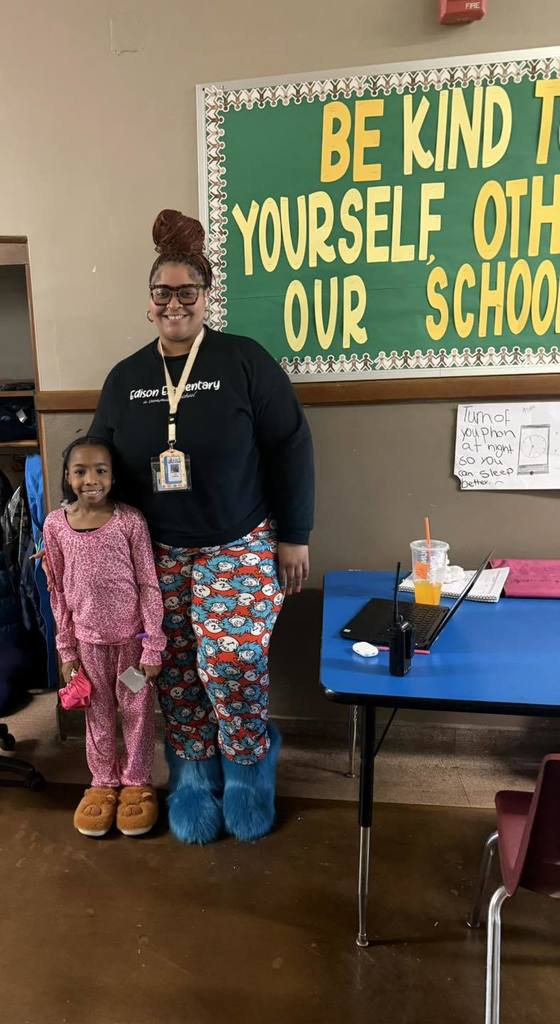 A student and a teacher wearing pajamas and smiling.