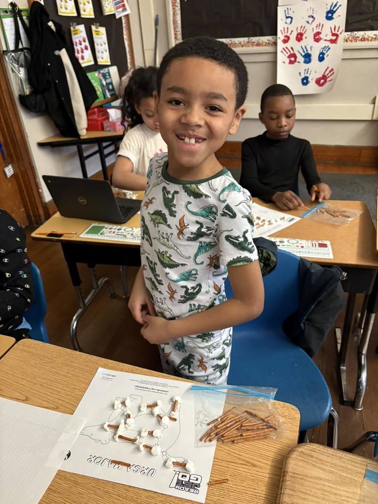 A young student wearing pajamas and smiling in class.