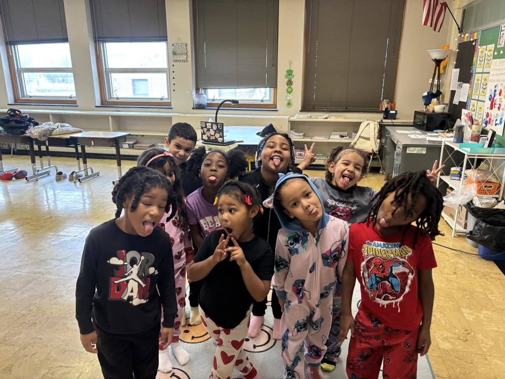 Students making funny faces in a classroom and wearing pajamas.