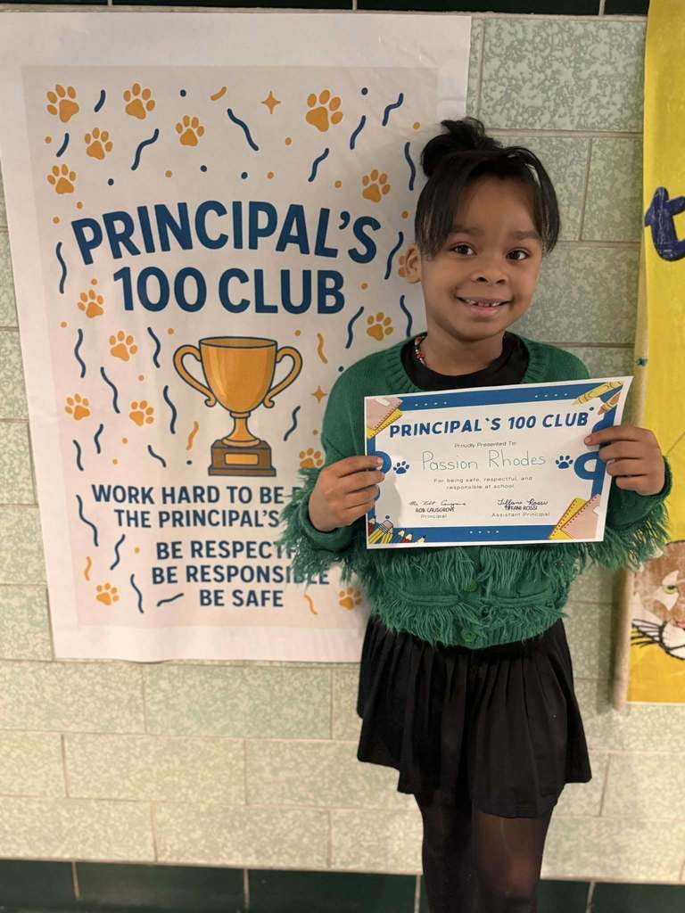A young girl that is wearing a green shirt is holding his Principal's 100 Club certificate. 
