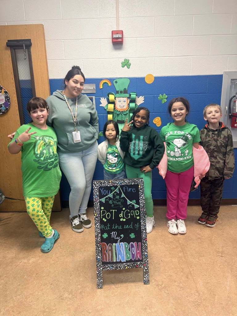 Students and teacher are wearing green and smiling. 