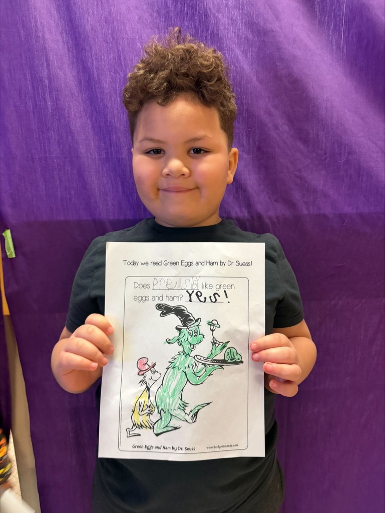 A student holding a paper he colored for Reading Across America week. 