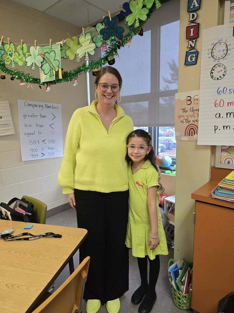 A student and a teacher are wearing the same shade of neon green.