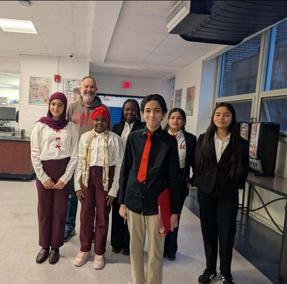 Students dressed professionally and a teacher in a gray hoodie. 
