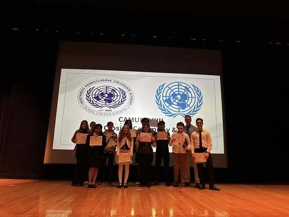 Students holding certificates on stage. 