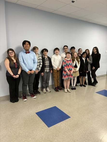 Students dressed professionally and smiling in a hall. 