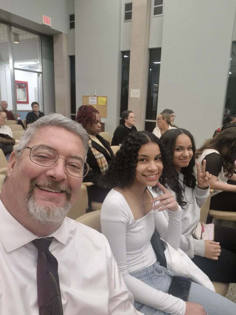 Students and teacher wearing white tops and smiling.