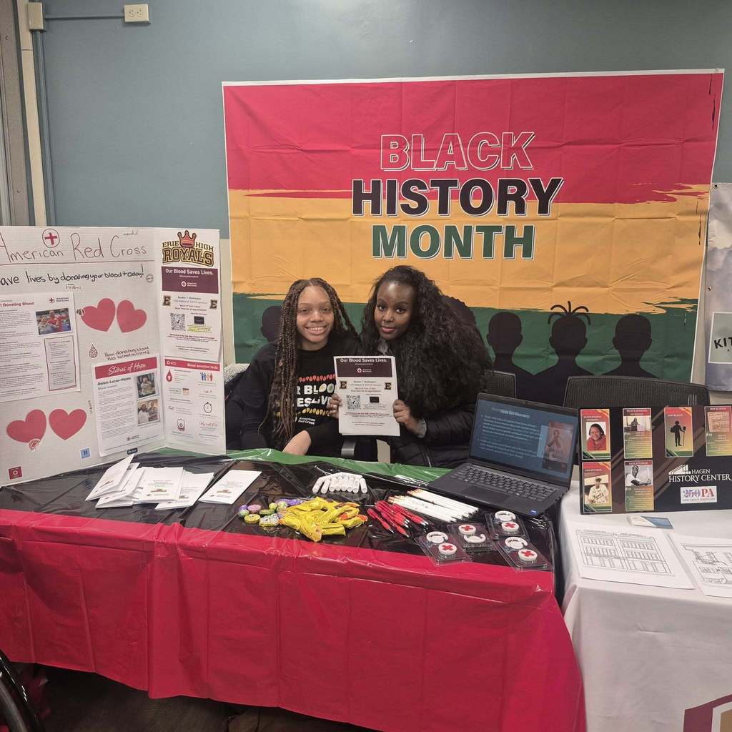 Two students sitting in front of a banner that says Black History Month and behind a table.