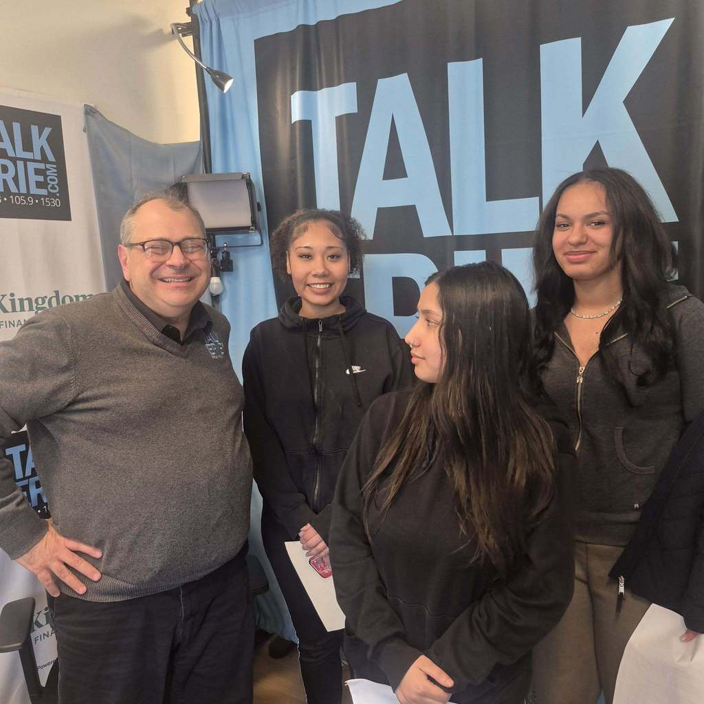 Students wearing black tops standing with a man wearing a gray shirt.