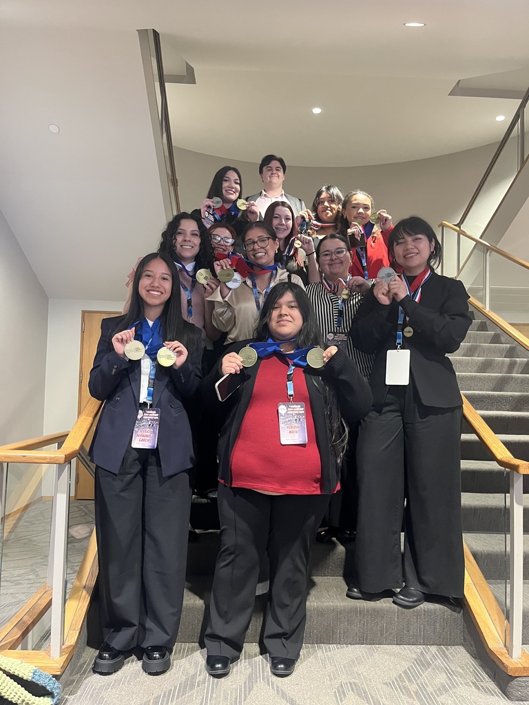 A group of people wearing medals and business attire, standing on a staircase. They are smiling.