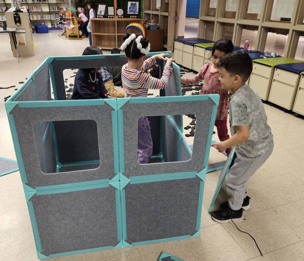 Kids building a house using fabric blocks. 