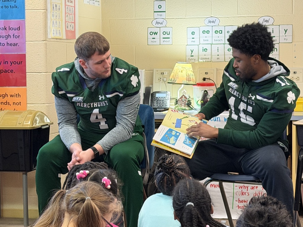 Mercyhurst University Football players reading to students in a classroom.