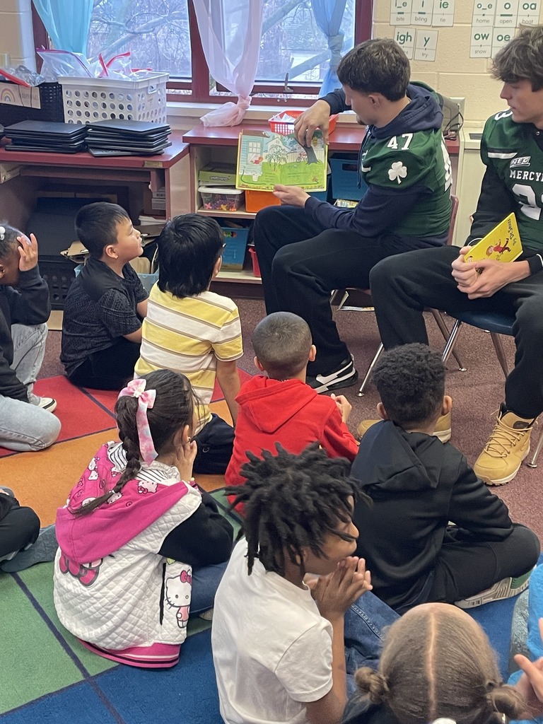 Mercyhurst University Football players reading to students in a classroom.