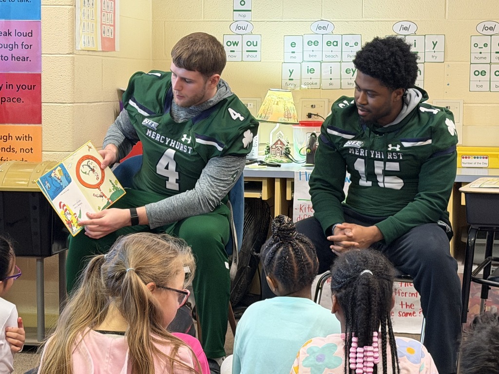 Mercyhurst University Football players reading to students in a classroom.