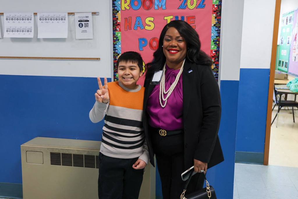 Dr. Natalyn Gibbs is smiling next to a student who is holding up a peace sign. 