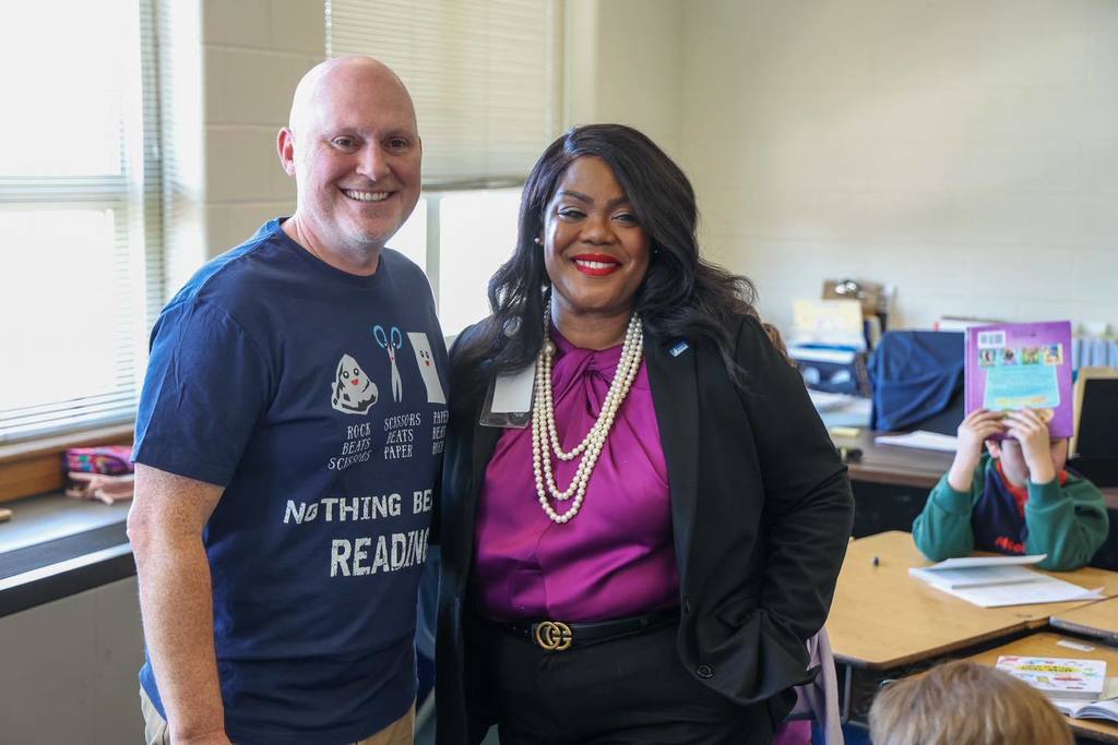 Dr. Natalyn Gibbs is standing and smiling next to a teacher. 