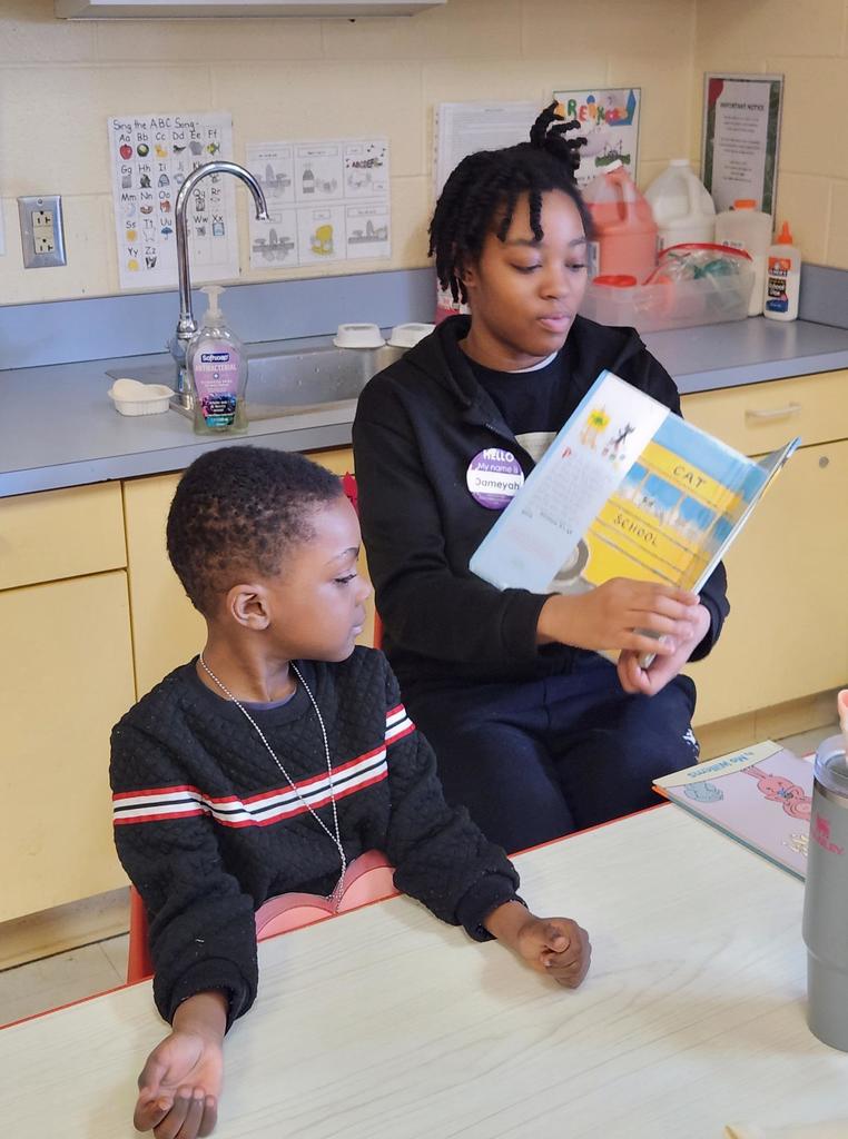 A student reading to a younger kid.