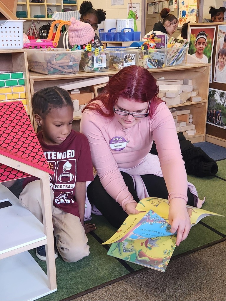 A student reading to a younger kid.