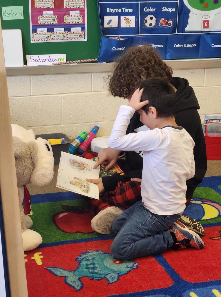 A student reading to a younger kid.