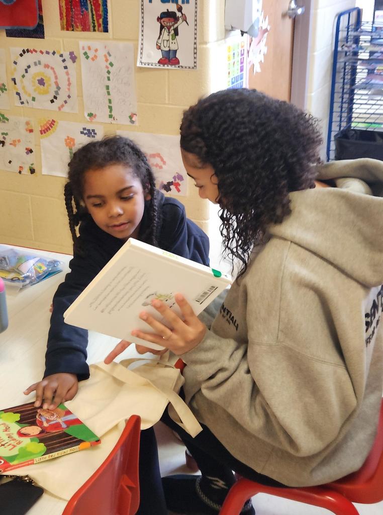 A student reading to a younger kid.