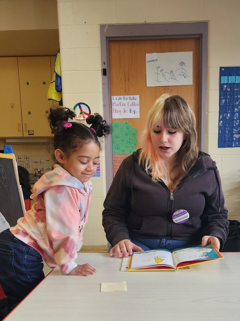 A student reading to a younger kid.